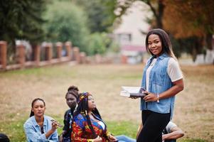 gruppo di cinque studenti universitari africani che trascorrono del tempo insieme nel campus nel cortile dell'università. amici afro neri che studiano. tema dell'educazione. foto