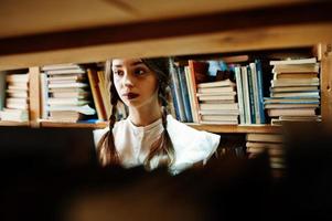 ragazza con le trecce in camicetta bianca alla vecchia biblioteca. foto