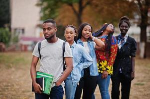 fila di studenti universitari africani del gruppo cinque che trascorrono del tempo insieme nel campus nel cortile dell'università. amici afro neri che studiano. tema dell'educazione. foto