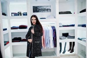 bruna splendida ragazza nella boutique del negozio di abbigliamento in abiti casual e cappotto grigio. foto