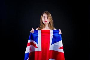 ragazza carina con bandiera della Gran Bretagna isolata su sfondo nero. foto
