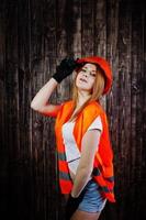 ingegnere donna in arancione protegge il casco e la giacca da costruzione su sfondo di legno. foto