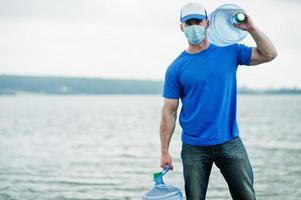 consegna acqua uomo indossare maschera medica protettiva per il viso durante la pandemia di coronavirus. foto