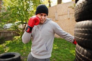 uomo pugile arabo in cappello che si allena per una dura lotta in palestra all'aperto. foto