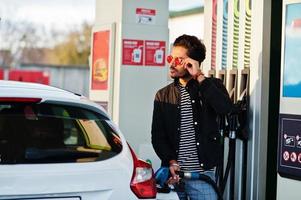 uomo del sud asiatico o maschio indiano che fa rifornimento di carburante alla sua macchina bianca sulla stazione di servizio. foto