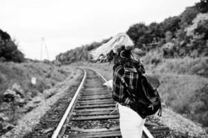 ritratto di una bella ragazza bionda in camicia scozzese che cammina sulla ferrovia con la mappa nelle sue mani. foto