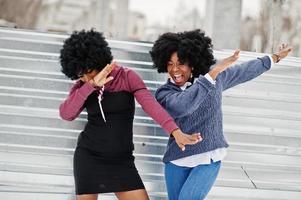 due capelli ricci donna afroamericana indossano maglioni poste in una giornata invernale, facendo dab. foto