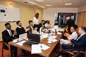 riunione del team aziendale multirazziale attorno al tavolo della sala riunioni, mani che battono le mani. foto