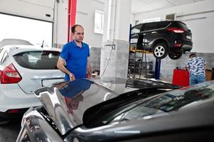 tema riparazione e manutenzione auto. meccanico in uniforme che lavora in servizio auto. foto