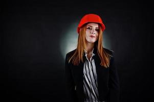 ingegnere donna in arancione protegge il casco su sfondo nero da studio. foto