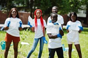 un gruppo di volontari africani felici tiene una lavagna vuota con il segno della comunità nel parco. concetto di volontariato, carità, persone ed ecologia in africa. foto