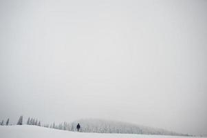 fotografo turistico uomo con zaino, in montagna con pini innevati. splendidi paesaggi invernali. natura gelata. foto