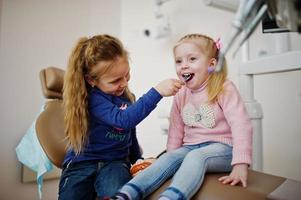 due piccole bambine carine alla poltrona del dentista. bambini dentali. foto