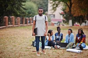 gruppo di cinque studenti universitari africani che trascorrono del tempo insieme nel campus nel cortile dell'università. amici afro neri che studiano. tema dell'educazione. foto