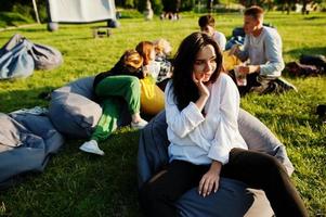 giovane gruppo multietnico di persone che guardano film al poof nel cinema all'aperto. primo piano ritratto di ragazza divertente. foto