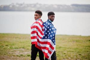 due adolescenti africani amici con bandiera americana al parco che indossano maschere mediche proteggono da infezioni e malattie quarantena del virus del coronavirus. foto