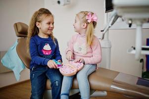 due piccole bambine carine alla poltrona del dentista. bambini dentali. foto