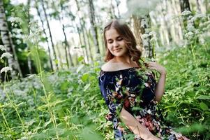 ritratto di una favolosa ragazza in un bel vestito con un'elegante acconciatura riccia in posa nella foresta o nel parco. foto