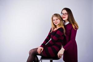 ragazze in abiti viola che si divertono e posano sulla sedia in studio. foto