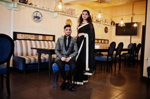 adorabile coppia indiana innamorata, indossata a saree e abito elegante, posata sul ristorante. foto