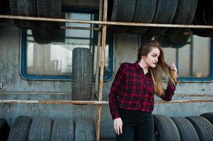 giovane ragazza hipster in camicia a scacchi nella zona di montaggio dei pneumatici. foto