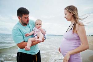 vacanze estive. genitori e persone attività all'aperto con i bambini. buone vacanze in famiglia. padre, madre incinta, figlia sulla spiaggia di sabbia del mare. foto