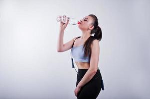 allegra attraente giovane donna fitness in top e leggings neri con corda per saltare e bottiglia d'acqua isolate su sfondo bianco. foto