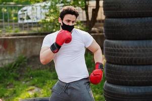 ritratto sport pugile arabo uomo in maschera medica nera boxe all'aperto durante la quarantena del coronavirus. foto