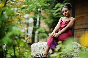 ritratto di una bella giovane donna africana naturale con i capelli afro. modello nero in abito di seta rossa. foto