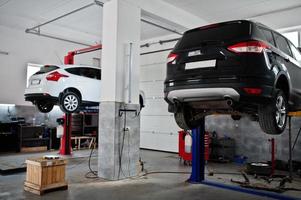 sollevamento di due auto in manutenzione presso stazione di servizio garage. foto