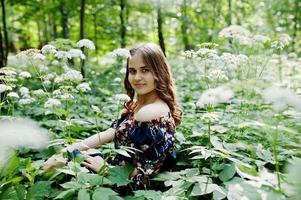 ritratto di una favolosa ragazza in un bel vestito con un'elegante acconciatura riccia in posa nella foresta o nel parco. foto