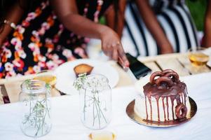 gruppo di ragazze afroamericane che celebrano la festa di compleanno e tagliano la torta all'aperto con decorazioni. foto