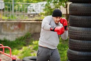 uomo pugile arabo in cappello che si allena per una dura lotta in palestra all'aperto. foto