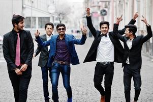 gruppo di 5 studenti indiani in giacca e cravatta in posa all'aperto, divertendosi e ballando. foto