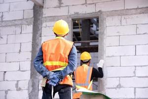 muratore in mattoni leggeri è fatto di argilla espansa. elementi nella costruzione in muratura il costruttore tiene i mattoni un uomo che indossa un elmetto in un cantiere edile foto