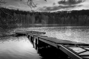 immagine in scala di grigi di un vecchio pontile rotto su un lago foto