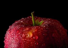 goccia d'acqua sulla superficie lucida della mela rossa su sfondo nero foto