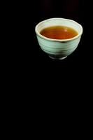 tè in tazza di ceramica su sfondo nero foto