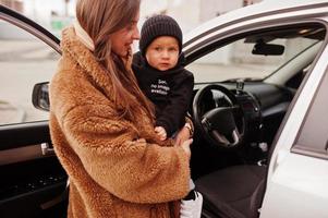 la giovane madre e il bambino stanno vicino alla loro auto suv. concetto di guida di sicurezza. foto