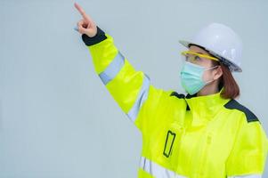 la bella donna asiatica dell'ingegnere indossa un vestito, occhiali e indossa un casco su sfondo bianco, la gente della Tailandia foto