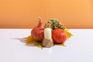 composizione creativa autunnale. ghirlanda di foglie secche, zucche e candela su sfondo bianco arancione. concetto di autunno autunno e giorno del ringraziamento. natura morta foto