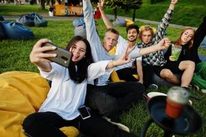 giovane gruppo multietnico di persone che guardano film al cinema all'aperto e fanno selfie al telefono. foto