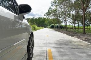 macchina bianca che guida sulla strada di campagna con piantagioni di alberi a lato della strada. andando avanti per viaggiare con la natura in Thailandia foto