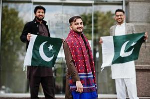 gruppo di pakistani che indossano abiti tradizionali salwar kameez o kurta con bandiere pakistane. foto