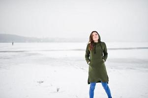 ragazza divertente indossare su felpa verde lunga e jeans, al lago ghiacciato in una giornata invernale. foto