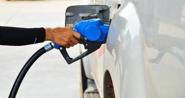 mano che tiene l'ugello diesel blu alla stazione di servizio, il concetto di crisi petrolifera, petrolio costoso foto