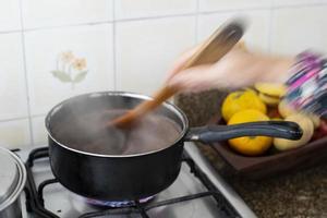 persona che mescola la padella dei fagioli con il fumo e le braccia in padella. foto