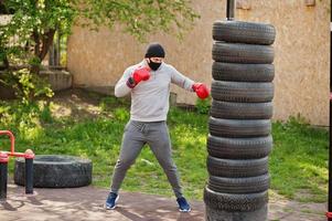 ritratto sport pugile arabo uomo in maschera medica nera boxe all'aperto durante la quarantena del coronavirus. foto