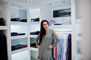bruna splendida ragazza nella boutique del negozio di abbigliamento in abito grigio. foto
