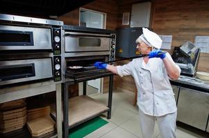 chef femminile che prepara pizza nella cucina del ristorante. foto